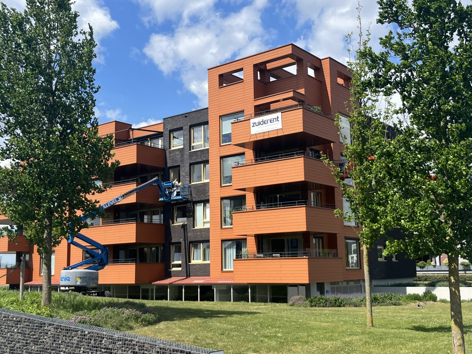 Buitenschilderwerk en onderhoud met een hoogwerker aan een appartementencomplex
