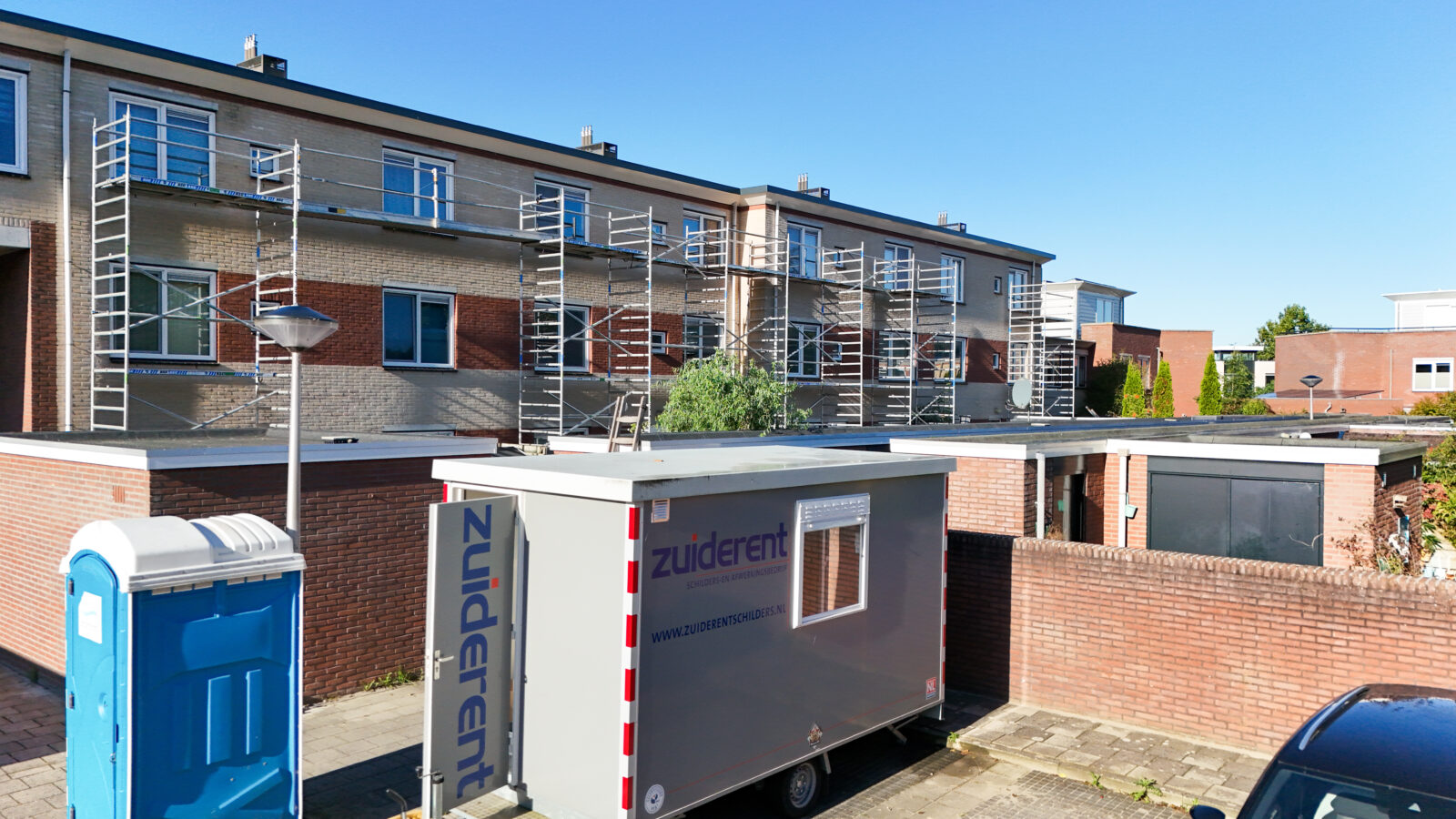 Buitenschilderwerk en onderhoud met steigers aan de achterkant van woningen.