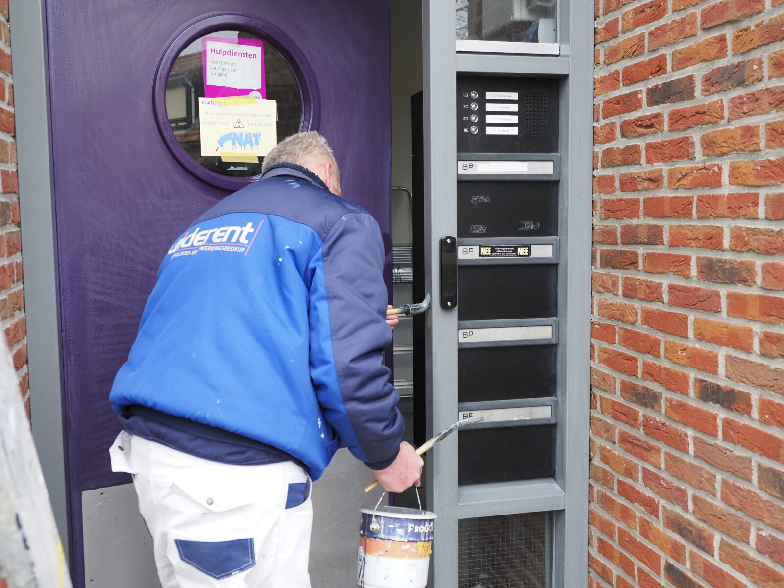 Buitenschilderwerk aan de deurpost van een appartementencomplex